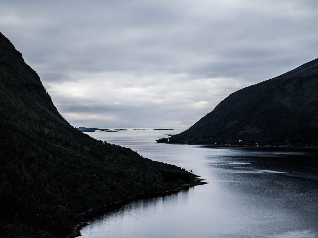 pexels photo 37968359 37968359 1 A tranquil view of a Norwegian fjord surrounded by mountains under a dramatic cloudy sky.